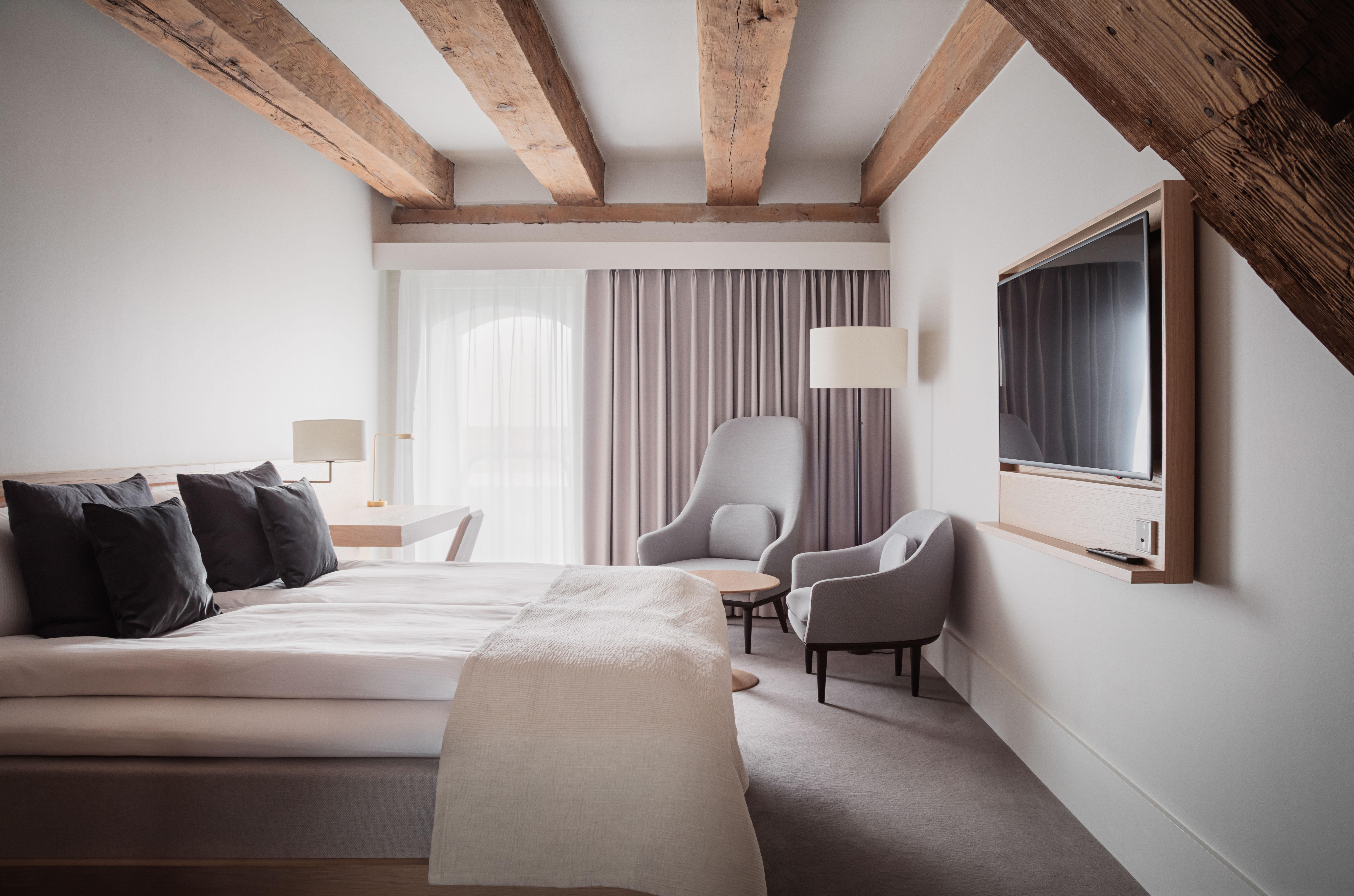 Copenhagen Admiral Hotel Esterno foto The photo shows a modern hotel room designed with a minimalist aesthetic. It features a spacious area with a large bed covered in white linens and decorative pillows. There are two armchairs—one in a light fabric and another more structured chair—sit