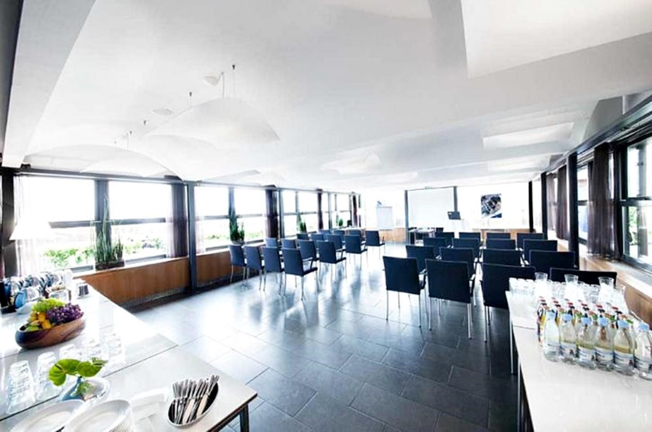 Copenhagen Admiral Hotel Esterno foto The photo depicts a modern conference room or meeting space. It features large windows that provide plenty of natural light and a view outside. The room is equipped with rows of dark blue chairs arranged for a presentation or meeting. There are also 
