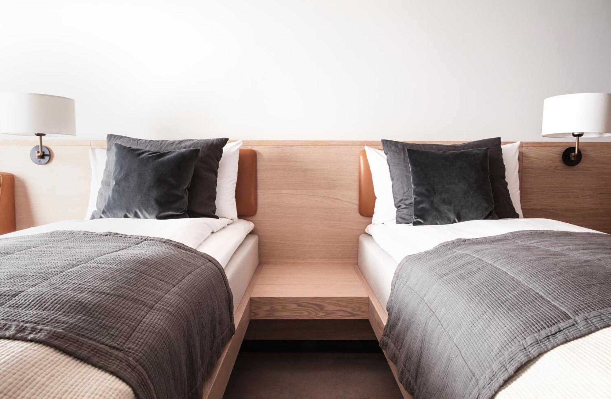 Copenhagen Admiral Hotel Esterno foto The photo shows a modern bedroom with two single beds positioned side by side. Each bed has a light-colored wooden headboard and is dressed with white bedding topped with dark gray blankets. There are decorative pillows on each bed, and the room has 
