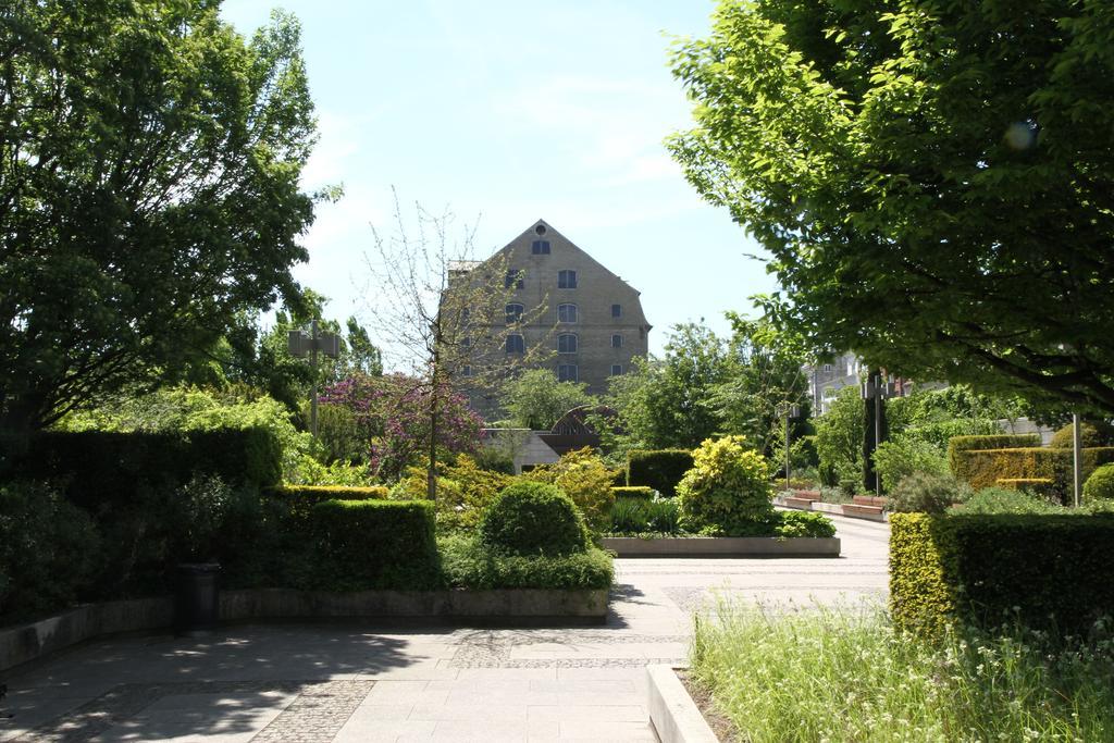 Copenhagen Admiral Hotel Esterno foto The photo shows a well-maintained park or garden area with lush greenery. In the foreground, there are various types of plants and shrubs arranged neatly, creating a pleasant landscape. A pathway runs through the area, leading towards a building in t